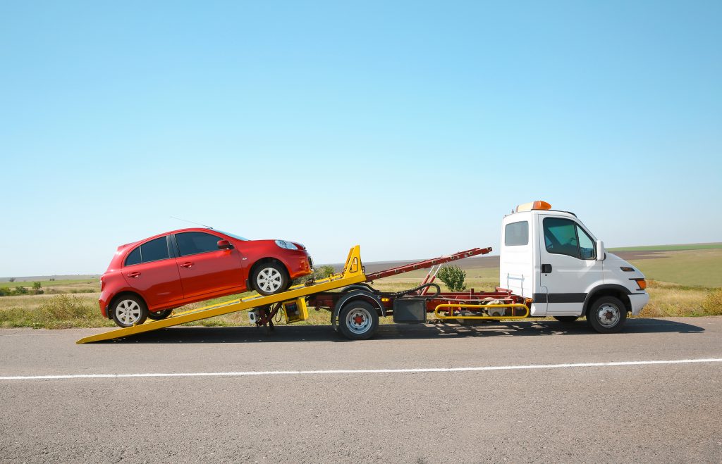 Tow truck with broken car on country road