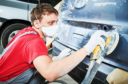 auto repairman grinding autobody